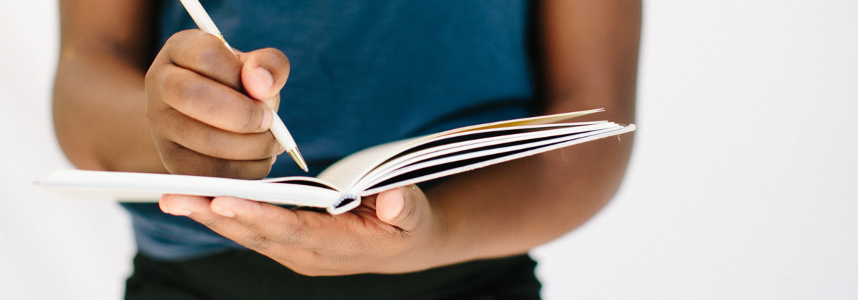Person holding a journal with a pen.
