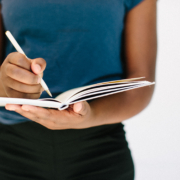Person holding a journal with a pen.