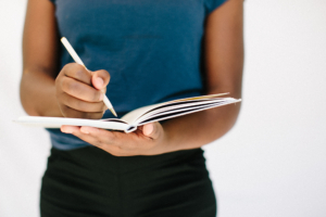 Person holding a journal with a pen.